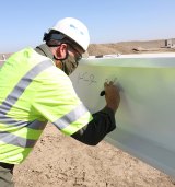 NAS Lemoore Commanding Officer Doug Peterson signs a beam during a "topping out" ceremony at the half-way point of construction on a new F 35C Lightning II hangar.